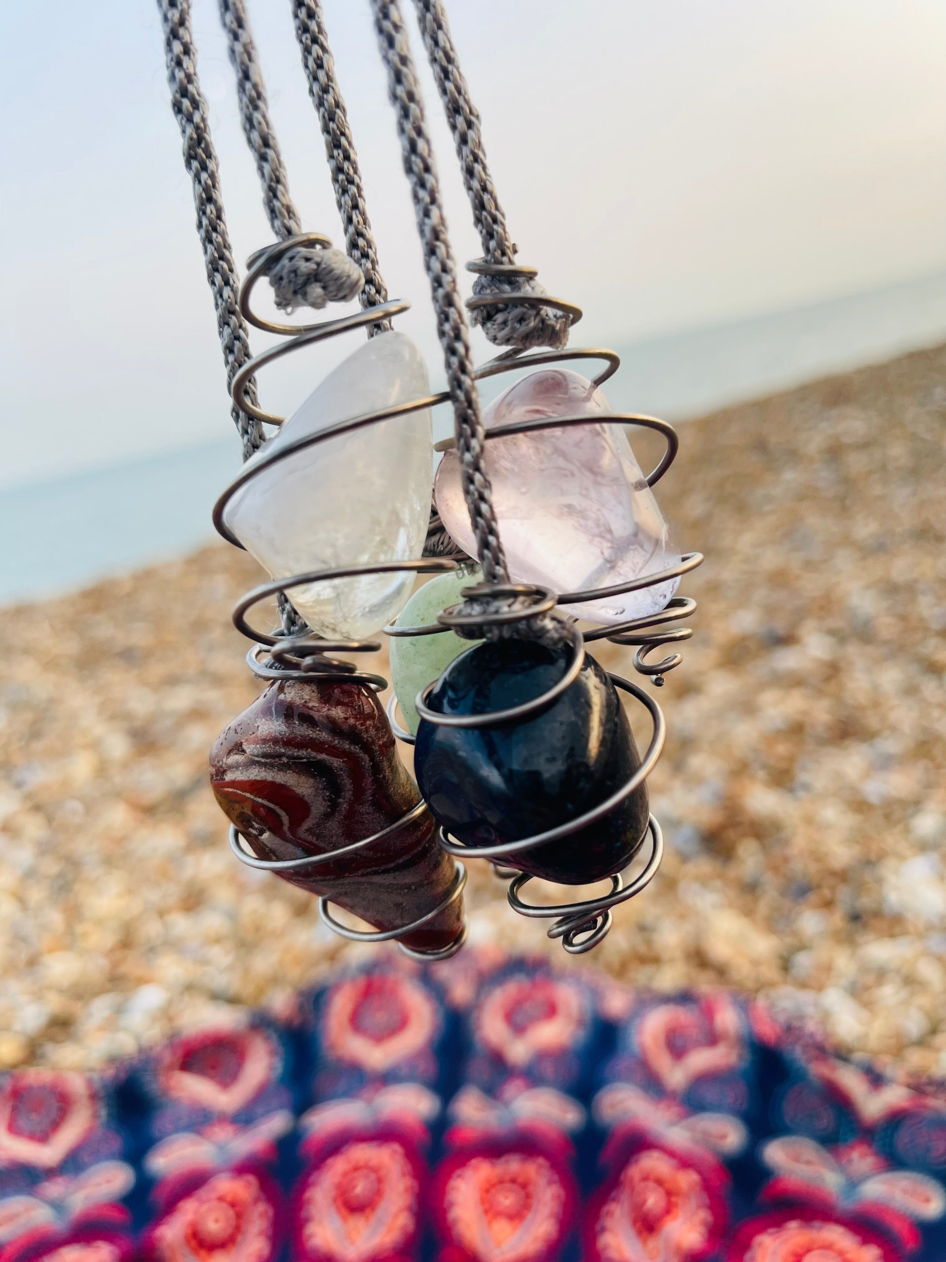 Blue Quartz spiral pendulum displayed alongside handcrafted Clear Quartz, Green Aventurine, Rose Quartz and Red Jasper spiral pendulums wrapped in titanium wire.