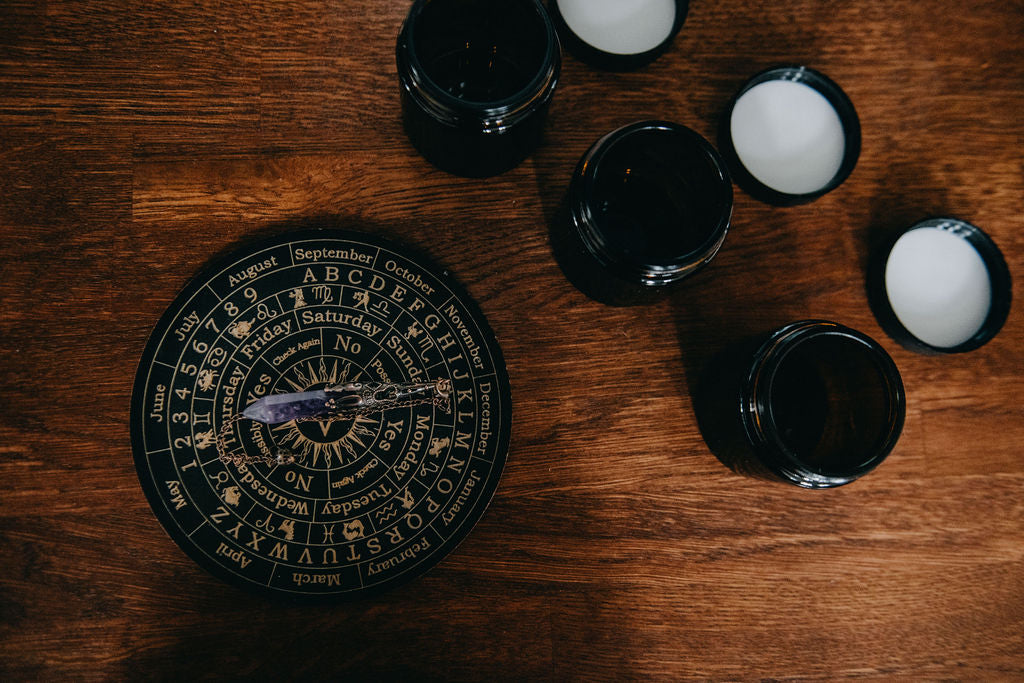 Black circular calendar or astrological chart on a wooden surface with candles.