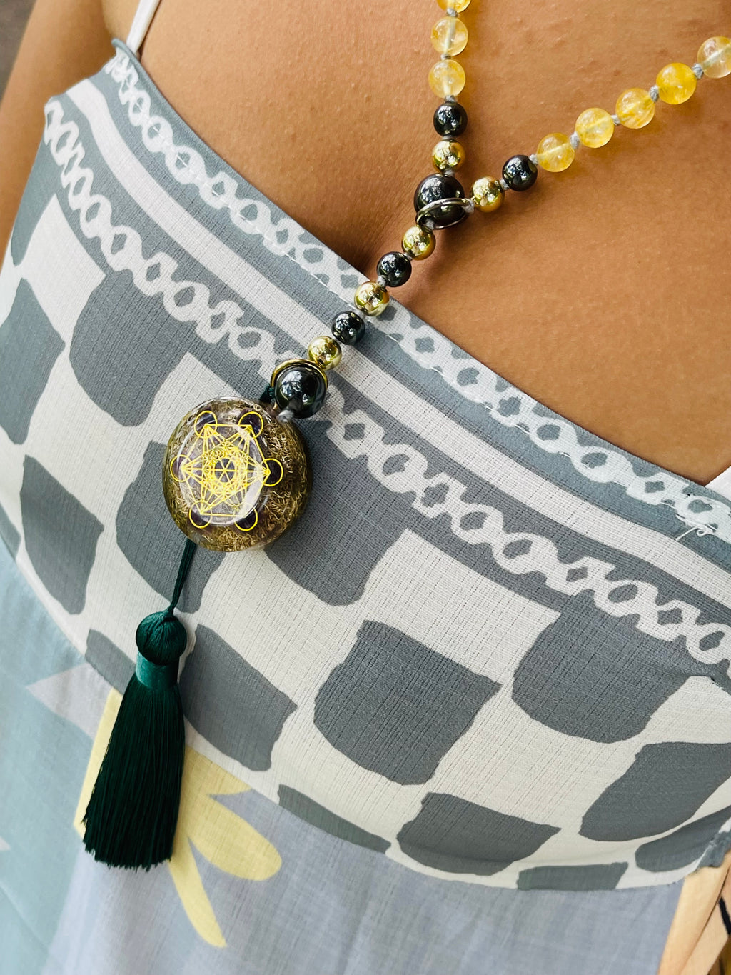 Path of Prosperity crystal mala worn as a necklace, featuring a Metatron's Cube talisman, citrine beads and an emerald green tassel.