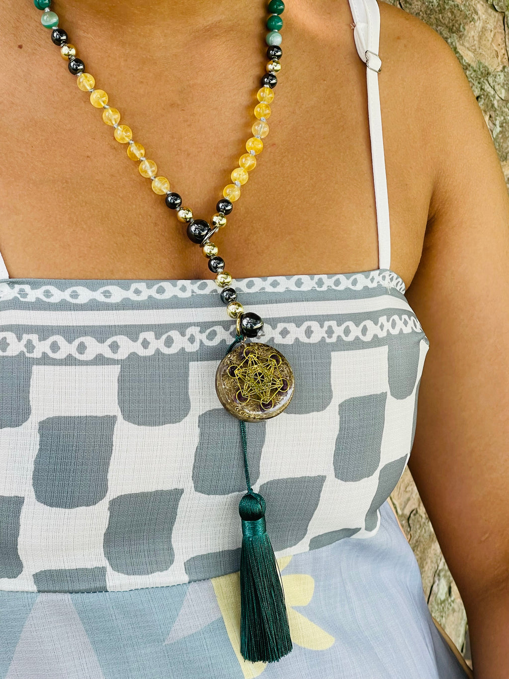 Path of Prosperity crystal mala worn as a necklace, featuring a Metatron's Cube talisman, citrine beads and an emerald green tassel.