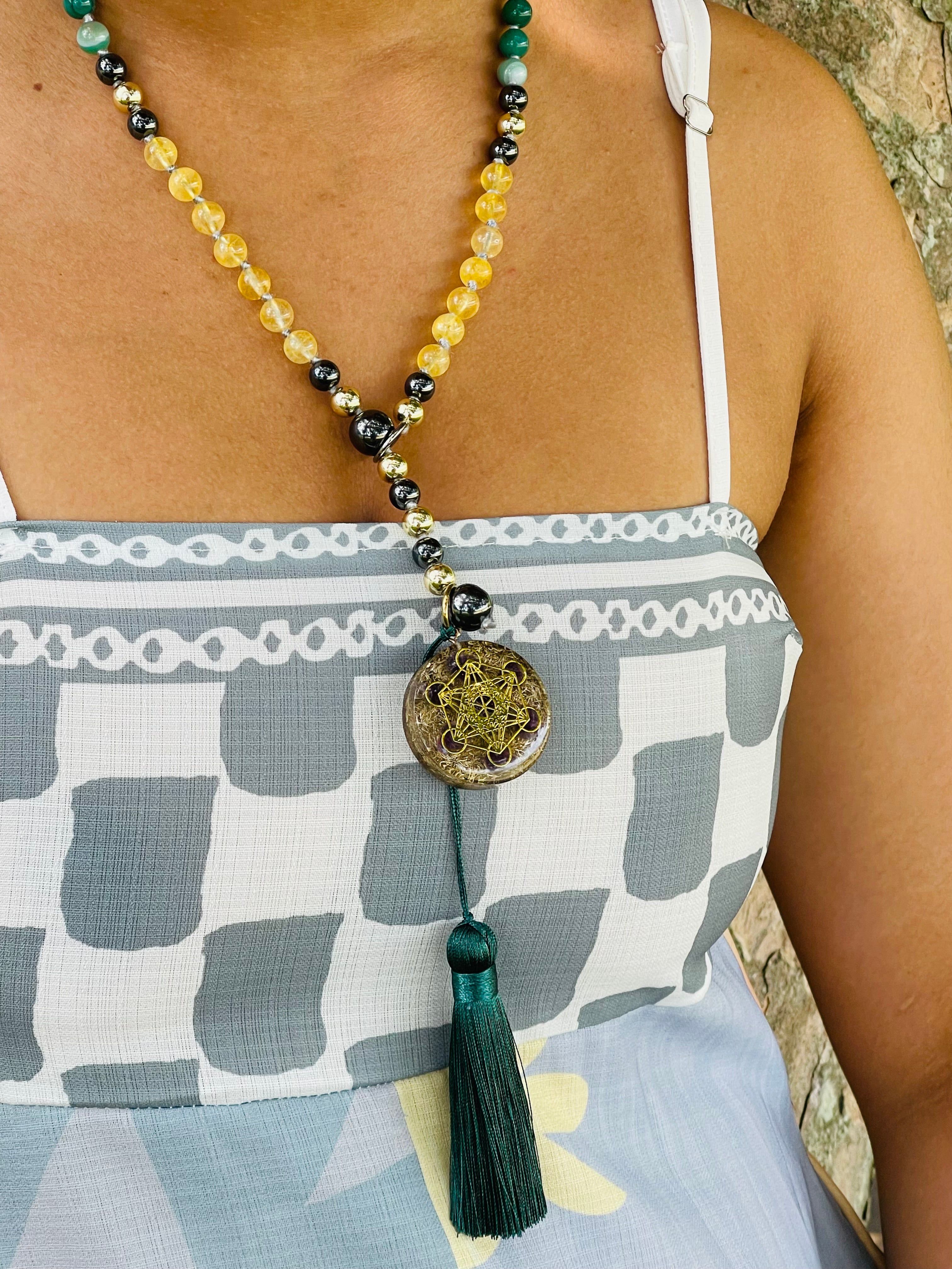 Path of Prosperity crystal mala worn as a necklace, featuring a Metatron's Cube talisman, citrine beads and an emerald green tassel.