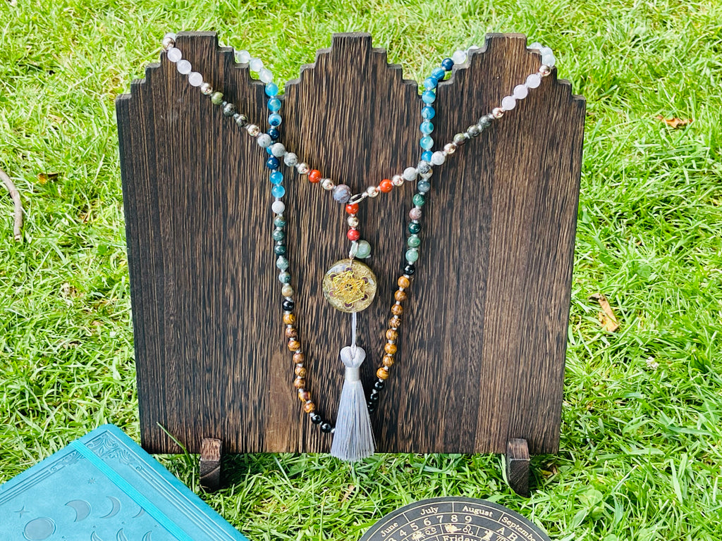Handcrafted bespoke crystal mala by Starlight Rituals displayed on a handcrafted wooden stand, showcasing the natural gemstone design, decorative focal pendant and premium rayon tassel.