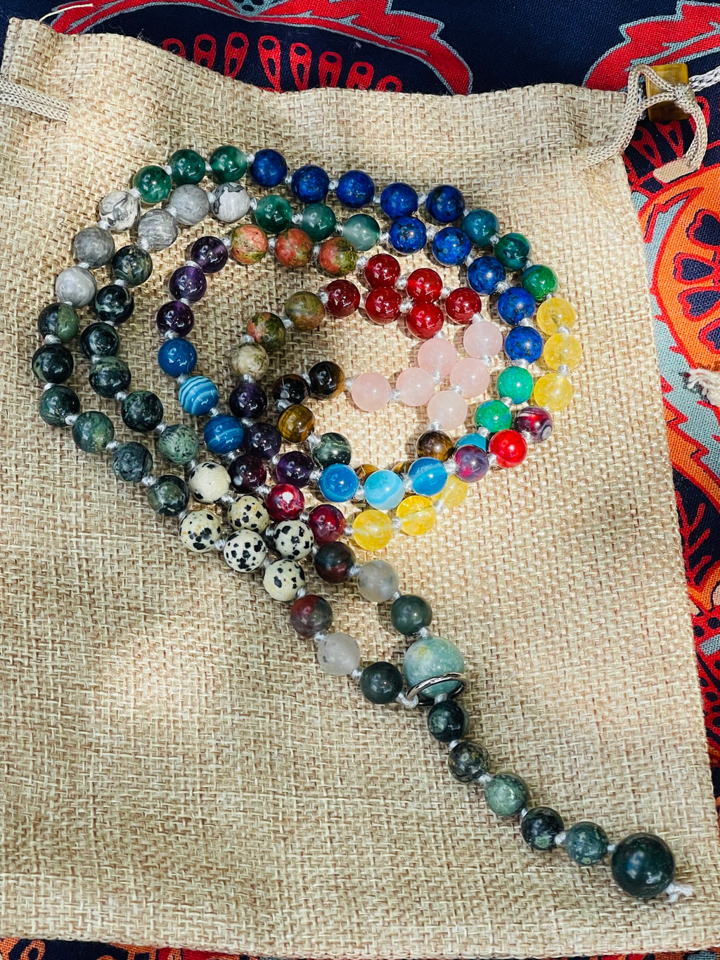 Handcrafted bespoke crystal mala by Starlight Rituals arranged in a heart shape on a natural hessian bag, showcasing the unique natural gemstone design.