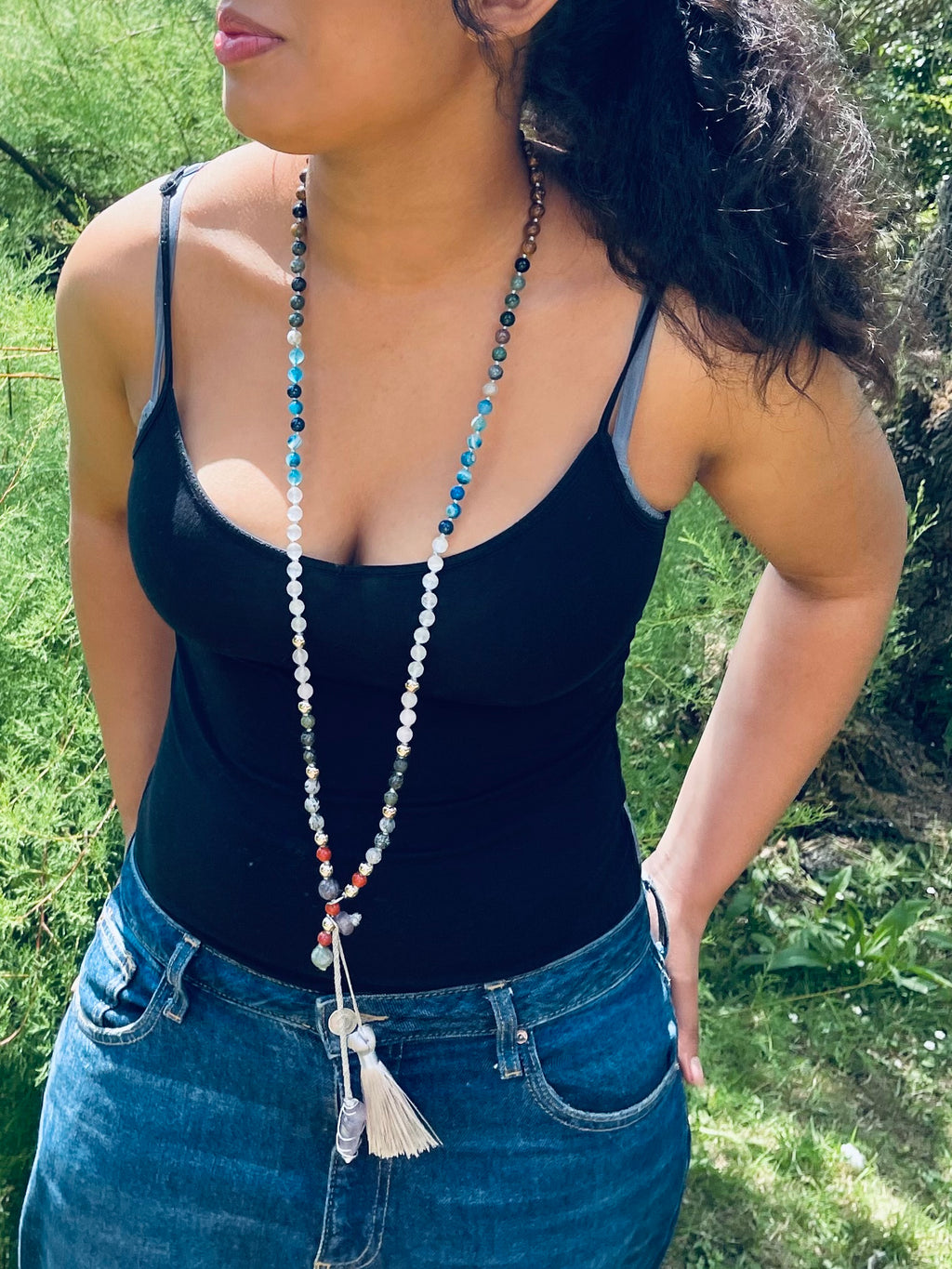 Model wearing a handcrafted bespoke crystal mala by Starlight Rituals featuring natural blue, white and silver gemstones with a handcrafted tassel.