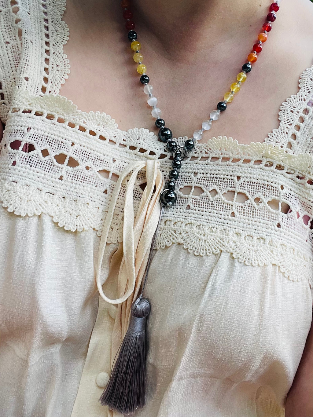 Handcrafted bespoke crystal mala by Starlight Rituals worn with a cream blouse, showing the natural drape, individually hand-knotted gemstones and premium rayon tassel.