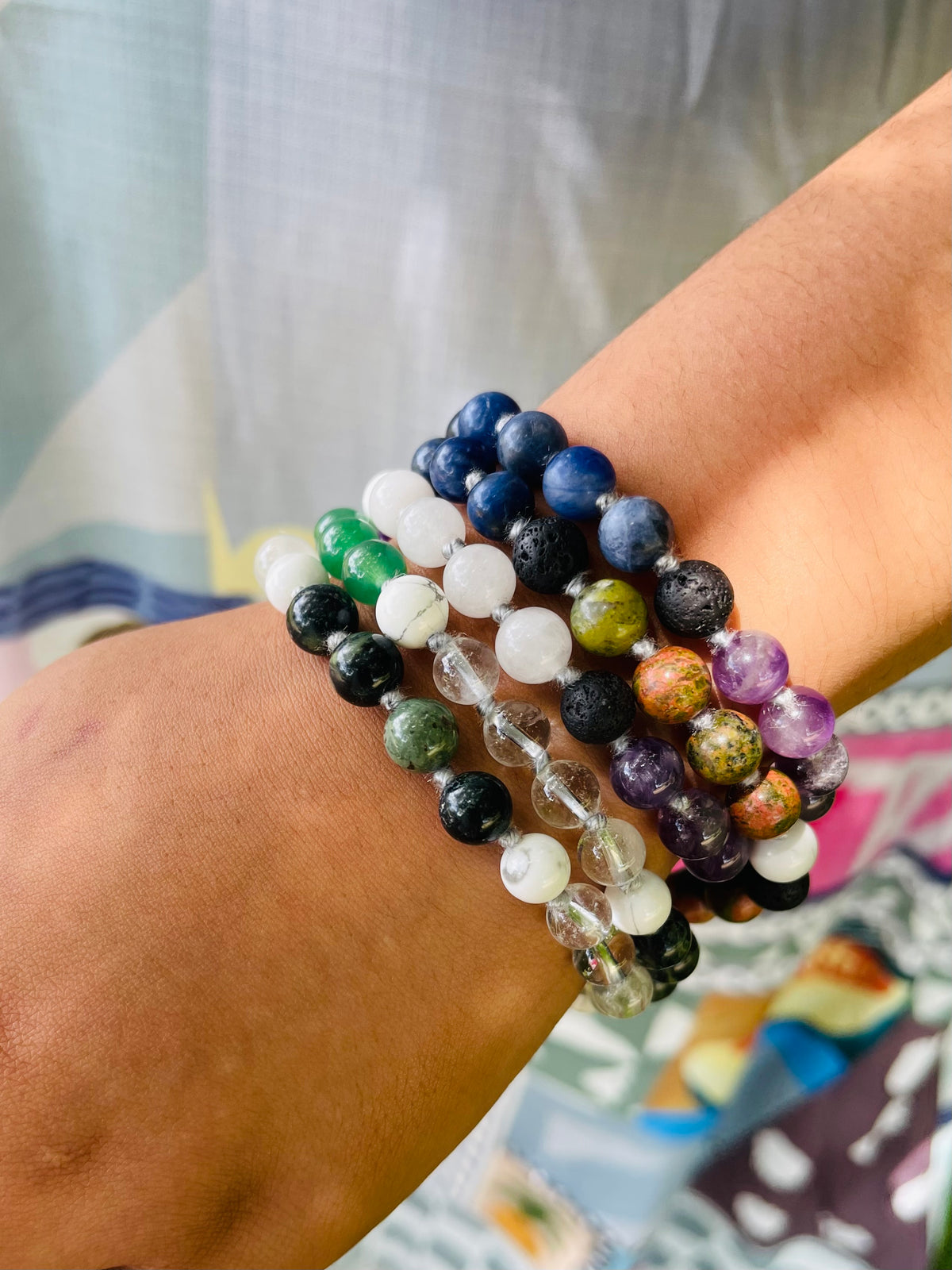 Starlight Rituals handcrafted gemstone mala wrapped around the wrist as a multi-layer bracelet, featuring polished blue, green, purple, white and clear crystal beads in an intricate, colourful design.