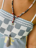 Handcrafted Starlight Rituals crystal mala worn as a long necklace, featuring multicoloured gemstone beads, silver-toned accent beads, a pale green focal crystal and a long silver-grey tassel.